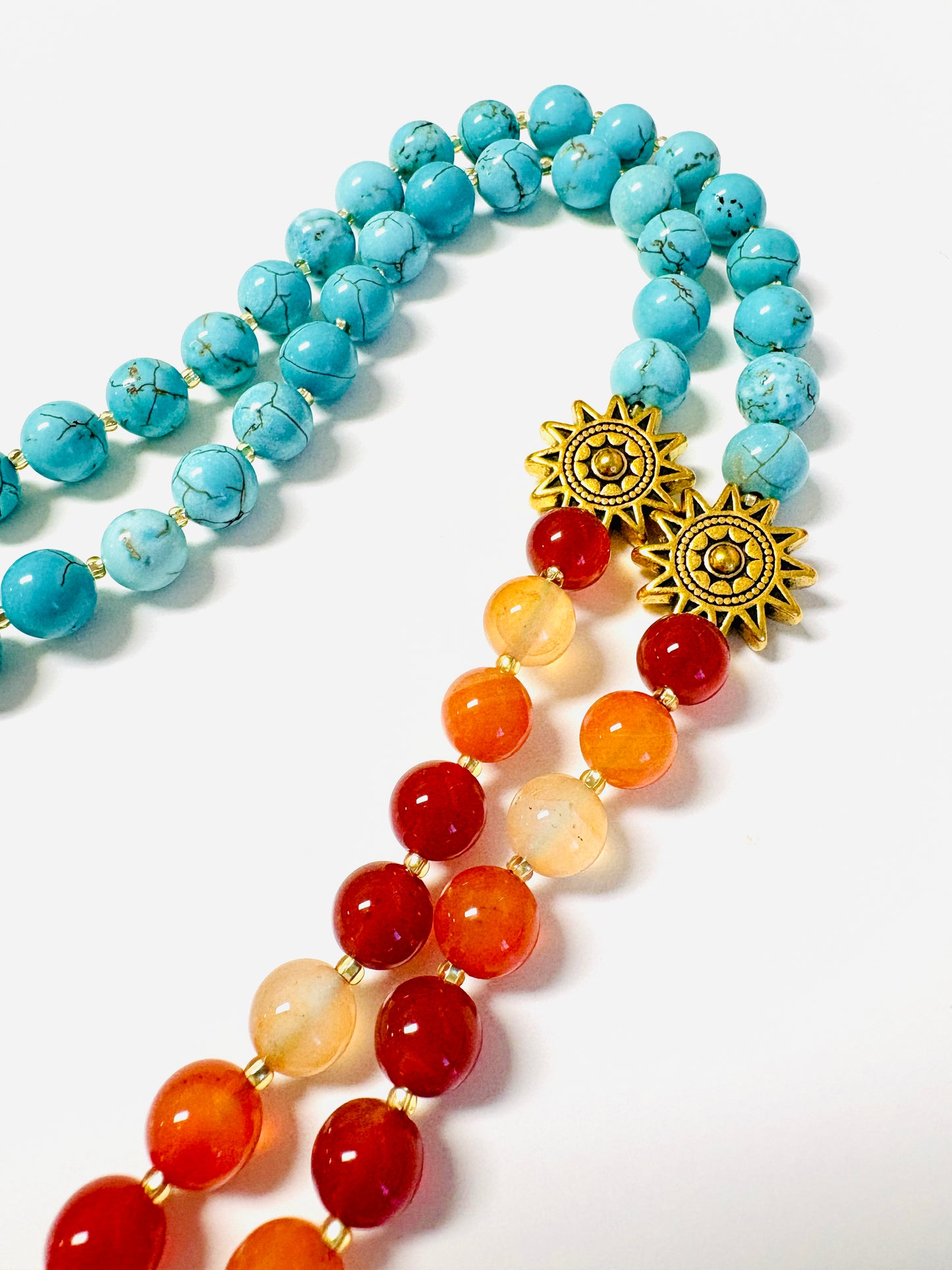 Close up of mala necklace with carnelian and turquoise beads and gold sun markers