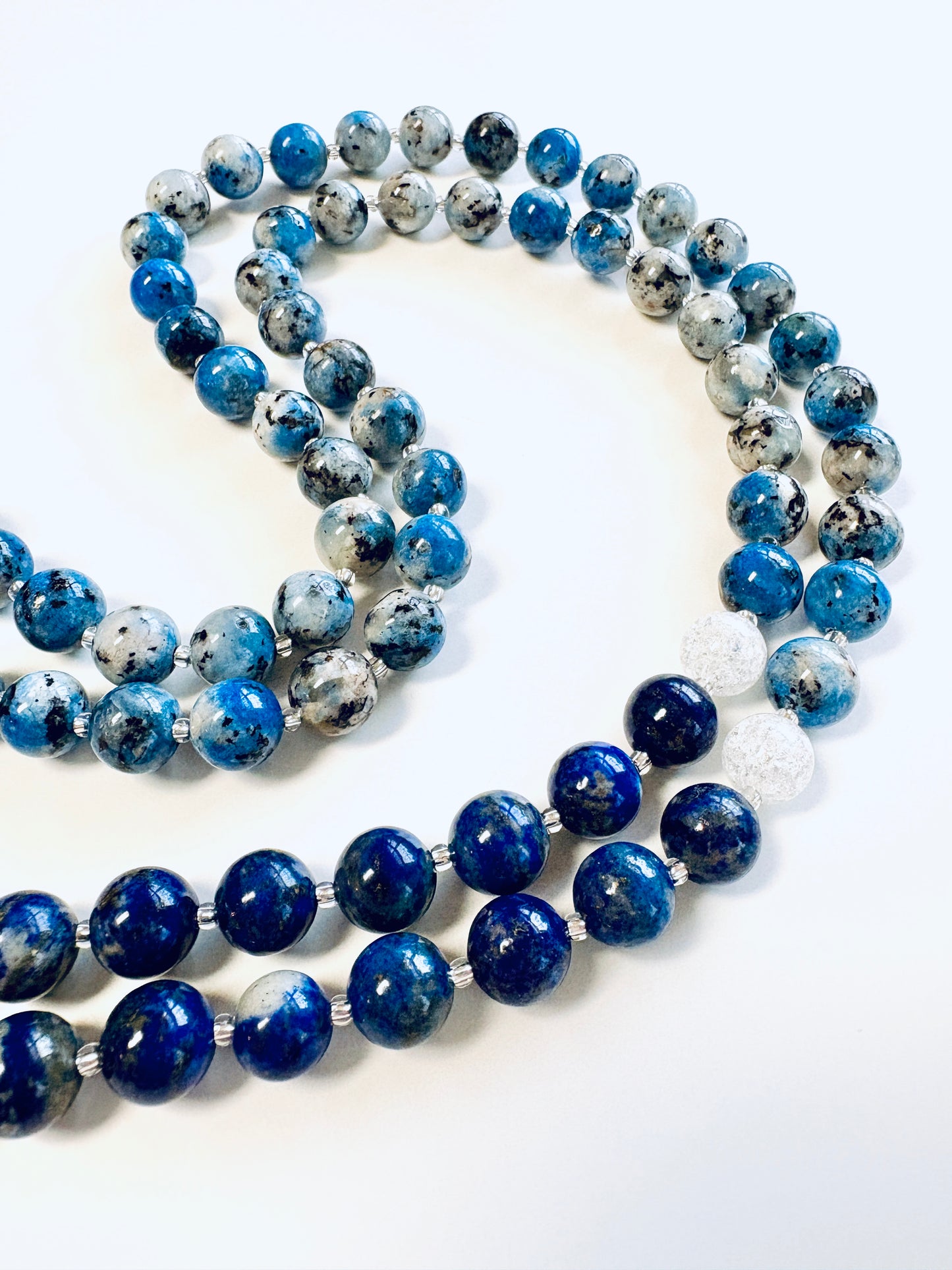 Close up of mala necklace with K2 and lapis lazuli beads on a white background