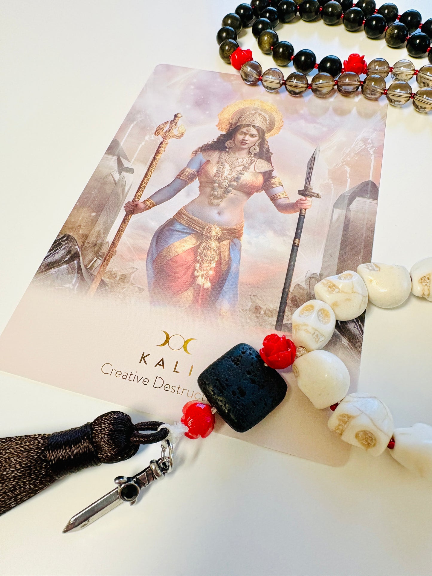 Close up of Goddess Kali mala necklace tassel with dagger charm and black lava stone guru bead